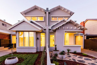This is an example of a large traditional two-storey white townhouse exterior in Melbourne with wood siding, a gable roof and a metal roof.