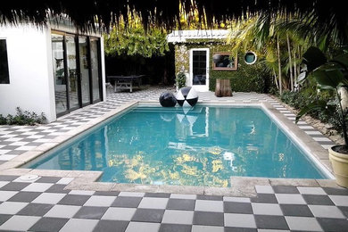 Photo of a mid-sized transitional backyard rectangular lap pool in Miami with a pool house and natural stone pavers.