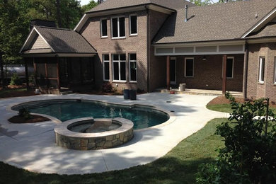 Example of a mid-sized classic backyard concrete and kidney-shaped lap hot tub design in Raleigh