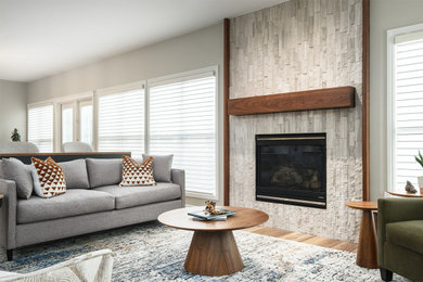 エドモントンにある高級な中くらいなコンテンポラリースタイルのおしゃれなLDK (ベージュの壁、ラミネートの床、標準型暖炉、積石の暖炉まわり、テレビなし、ベージュの床) の写真
