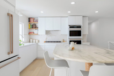 Example of a minimalist single-wall light wood floor and beige floor enclosed kitchen design in Omaha with an undermount sink, flat-panel cabinets, white cabinets, marble countertops, beige backsplash, porcelain backsplash, white appliances, an island and white countertops