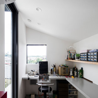 Photo of a modern home office and library in Yokohama with white walls, concrete flooring, a built-in desk and grey floors.