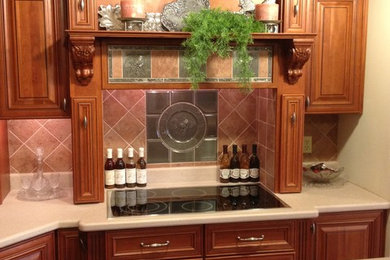 Enclosed kitchen - mid-sized traditional l-shaped travertine floor enclosed kitchen idea in Philadelphia with raised-panel cabinets, medium tone wood cabinets, laminate countertops, brown backsplash, ceramic backsplash, stainless steel appliances and an island