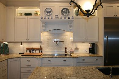 Inspiration for a large timeless l-shaped medium tone wood floor and brown floor open concept kitchen remodel in Atlanta with a double-bowl sink, recessed-panel cabinets, white cabinets, granite countertops, white backsplash, ceramic backsplash, stainless steel appliances and an island