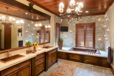 Elegant gray tile and stone tile drop-in bathtub photo with a drop-in sink, recessed-panel cabinets and dark wood cabinets