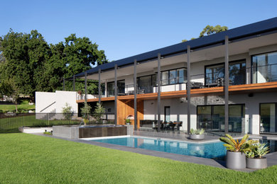 Design ideas for an expansive backyard l-shaped lap pool in Melbourne with a water feature and concrete pavers.