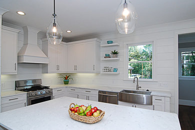 Inspiration for a mid-sized transitional l-shaped medium tone wood floor and brown floor kitchen remodel in Other with a farmhouse sink, shaker cabinets, white cabinets, marble countertops, white backsplash, wood backsplash, stainless steel appliances and an island
