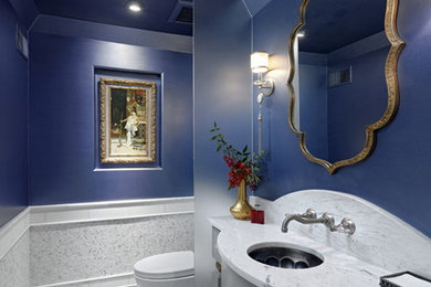This is an example of a traditional powder room in DC Metro with furniture-like cabinets, grey cabinets, white tile, marble, blue walls, marble floors, an undermount sink, marble benchtops, white floor and white benchtops.