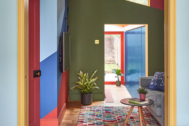 Exempel på ett eklektiskt vardagsrum, med flerfärgade väggar, ljust trägolv och en väggmonterad TV