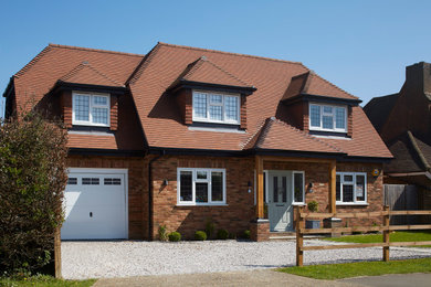 This is an example of a medium sized traditional two floor brick and front house exterior in Buckinghamshire with an orange house, a hip roof, a tiled roof and a brown roof.