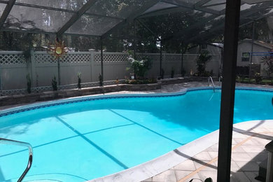This is an example of a mid-sized traditional backyard custom-shaped lap pool in Orlando with a water feature and concrete pavers.
