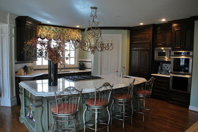Example of a large classic medium tone wood floor eat-in kitchen design in Kansas City with a single-bowl sink, raised-panel cabinets, dark wood cabinets, marble countertops, white backsplash, stainless steel appliances and an island