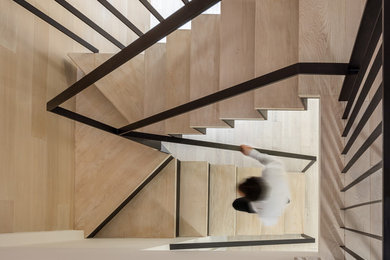 Large contemporary wood u-shaped staircase in New York with metal risers and metal railing.