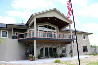 Example of a large eclectic beige two-story stucco house exterior design in Wichita with a hip roof and a mixed material roof