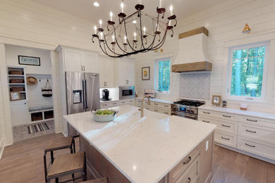 Open concept kitchen - large farmhouse u-shaped medium tone wood floor and brown floor open concept kitchen idea in Other with a farmhouse sink, shaker cabinets, white cabinets, quartz countertops, white backsplash, wood backsplash, stainless steel appliances, an island and white countertops