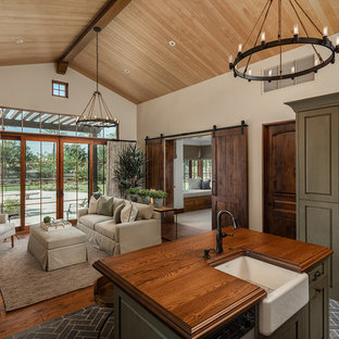 Diseño de cocina mediterránea, abierta, con fregadero sobremueble, armarios con paneles con relieve, puertas de armario beige, encimera de madera, suelo de madera oscura y una isla