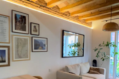 Modelo de salón abierto y blanco y madera mediterráneo pequeño con paredes blancas, suelo de madera clara, televisor independiente, suelo marrón, ladrillo, cortinas y vigas vistas