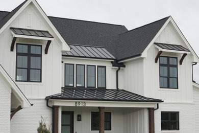 Example of a farmhouse white two-story exterior home design in Raleigh with a black roof