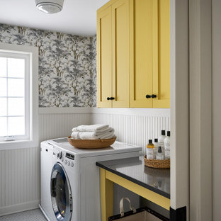 Bild på en mellanstor lantlig svarta parallell svart tvättstuga enbart för tvätt, med skåp i shakerstil, gula skåp, bänkskiva i kvarts, beige stänkskydd, beige väggar, klinkergolv i keramik, en tvättmaskin och torktumlare bredvid varandra och vitt golv