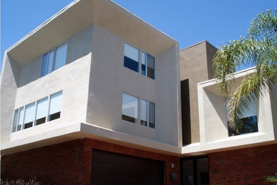 Large trendy beige two-story stucco flat roof photo in Los Angeles