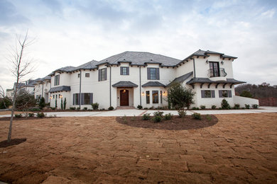 Huge traditional white two-story stucco exterior home idea in Dallas with a clipped gable roof