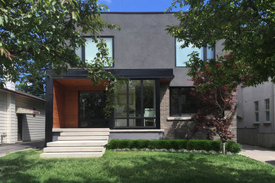 Example of a mid-sized trendy gray two-story stucco flat roof design in Toronto