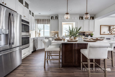 Inspiration for a timeless l-shaped light wood floor eat-in kitchen remodel in Salt Lake City with recessed-panel cabinets, white cabinets, beige backsplash, stainless steel appliances and an island
