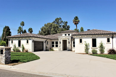 Photo of a mediterranean white house exterior in Los Angeles with a hip roof and a tile roof.