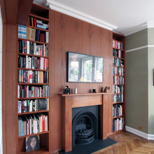 Inredning av ett 50 tals mycket stort hemmabibliotek, med en standard öppen spis, en spiselkrans i trä, gröna väggar, mellanmörkt trägolv och ett fristående skrivbord