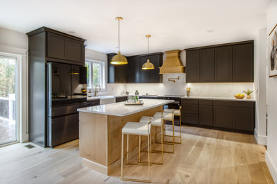 Inspiration for a mid-sized modern l-shaped light wood floor and brown floor eat-in kitchen remodel in Providence with a farmhouse sink, shaker cabinets, brown cabinets, white backsplash, black appliances, an island and white countertops