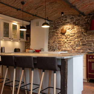 Mediterrane Küche mit Schrankfronten mit vertiefter Füllung, weißen Schränken, Küchenrückwand in Grau, bunten Elektrogeräten, Backsteinboden, Kücheninsel, rotem Boden und grauer Arbeitsplatte in Frankfurt am Main