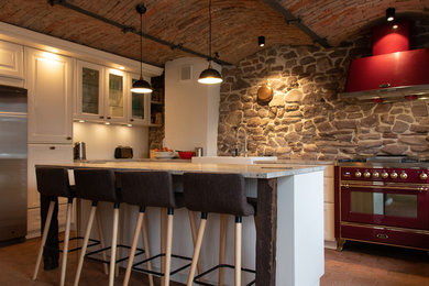 Inspiration for a mediterranean kitchen in Frankfurt with recessed-panel cabinets, white cabinets, grey splashback, coloured appliances, brick floors, with island, red floor and grey benchtop.