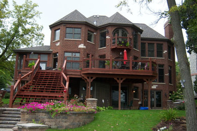 Example of a large classic brown three-story brick house exterior design in Chicago with a hip roof and a shingle roof