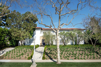 Inspiration for a large mediterranean white two-story stucco exterior home remodel in Los Angeles with a hip roof
