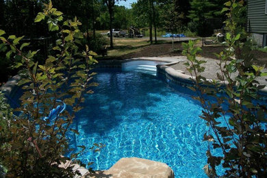 Diseño de piscina con fuente en patio trasero con adoquines de piedra natural
