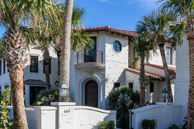 Large mediterranean beige two-story brick house exterior idea in Jacksonville with a hip roof and a tile roof