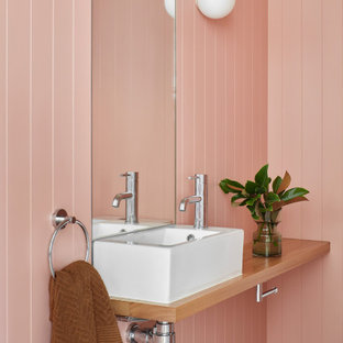 Mid-sized contemporary bathroom in Melbourne with medium wood cabinets, pink walls, a pedestal sink, wood benchtops, brown benchtops, a single vanity, a floating vanity and panelled walls.