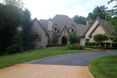 Large elegant gray two-story stone house exterior photo with a clipped gable roof and a shingle roof