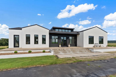 Large trendy white one-story stucco exterior home photo in Little Rock with a shingle roof and a black roof