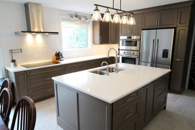 Example of a mid-sized trendy l-shaped porcelain tile and gray floor eat-in kitchen design in Toronto with an undermount sink, recessed-panel cabinets, brown cabinets, quartz countertops, white backsplash, stainless steel appliances, an island and white countertops