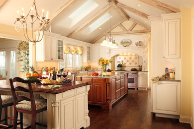 Inspiration for a large timeless l-shaped dark wood floor eat-in kitchen remodel in New York with a farmhouse sink, raised-panel cabinets, white cabinets, granite countertops, white backsplash, ceramic backsplash, stainless steel appliances and two islands