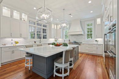 Example of a large transitional u-shaped medium tone wood floor and orange floor kitchen design in Atlanta with an undermount sink, flat-panel cabinets, white cabinets, gray backsplash, subway tile backsplash, stainless steel appliances, an island and white countertops