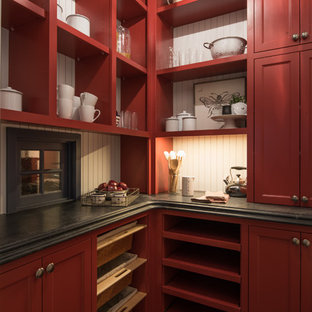 Cette photo montre une arrière-cuisine chic en L de taille moyenne avec un évier de ferme, un placard avec porte à panneau encastré, des portes de placard rouges, un plan de travail en inox, une crédence grise, une crédence en dalle de pierre, un électroménager en acier inoxydable, un sol en bois foncé, 2 îlots et un sol marron.