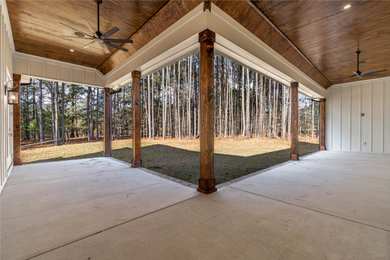 This is an example of a large traditional concrete porch design in Raleigh with a roof extension.