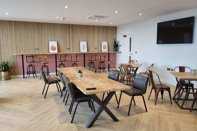Design ideas for a large industrial open plan dining room in Dorset with beige walls, ceramic flooring, brown floors, a drop ceiling, panelled walls and a feature wall.