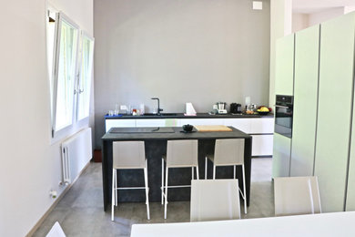 This is an example of a large modern galley eat-in kitchen in Other with a double-bowl sink, laminate benchtops, stainless steel appliances, porcelain floors, with island, grey floor and black benchtop.