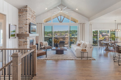 Open concept medium tone wood floor, vaulted ceiling and shiplap wall living room photo in Denver with a standard fireplace, a stone fireplace and a wall-mounted tv
