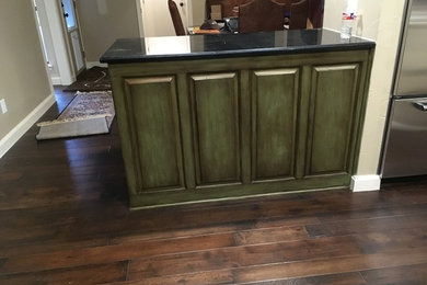 Mid-sized southwest l-shaped medium tone wood floor eat-in kitchen photo in Dallas with raised-panel cabinets, distressed cabinets, granite countertops, stainless steel appliances and two islands