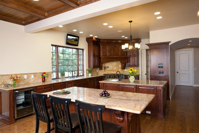 Kitchen - traditional kitchen idea in Santa Barbara with an undermount sink, raised-panel cabinets, medium tone wood cabinets, granite countertops, beige backsplash, stone tile backsplash and stainless steel appliances