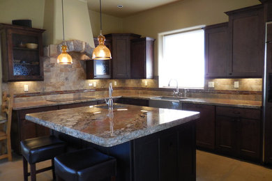 Inspiration for a rustic concrete floor kitchen remodel in Phoenix with a farmhouse sink, flat-panel cabinets, dark wood cabinets, granite countertops, multicolored backsplash, glass tile backsplash, stainless steel appliances and an island